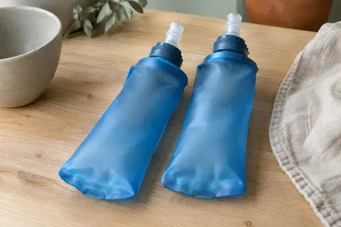 Deux flasques souples bleues en TPU, avec valve à morsure, posées sur une table en bois clair