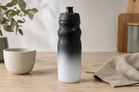Bidon de vélo Glekglek noir et blanc avec valve buccale, posé sur une table en bois clair.