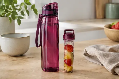 Gourde Uzspace rouge violacé en Tritan avec bouchon à protection et infuseur amovible posé à côté