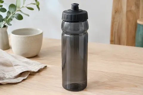 Bidon de vélo Zefal translucide noir de grande contenance posé sur une table en bois clair.